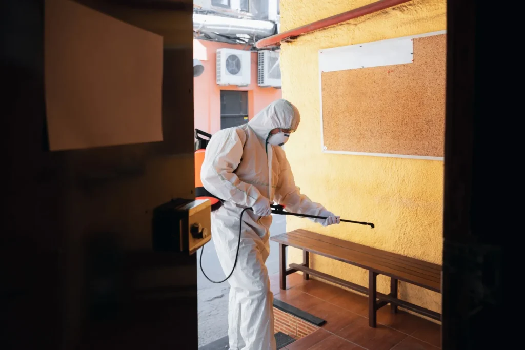 Disinfection services. Man in protective suit spraying disinfectant on a bench. Professional sanitation and deep cleaning in DMV.