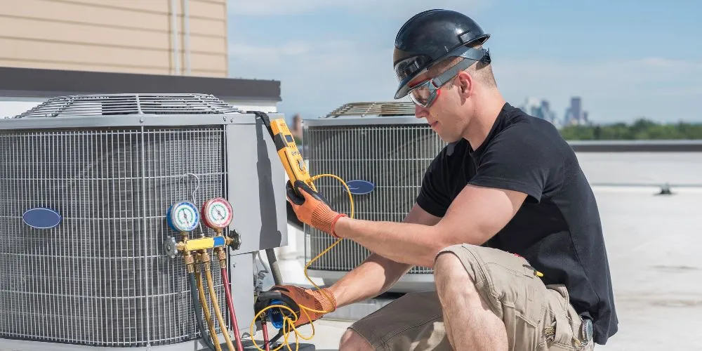 HVAC technician in DMV checking air conditioning system on a rooftop. Expert AC repair and maintenance services for optimal cooling performance.