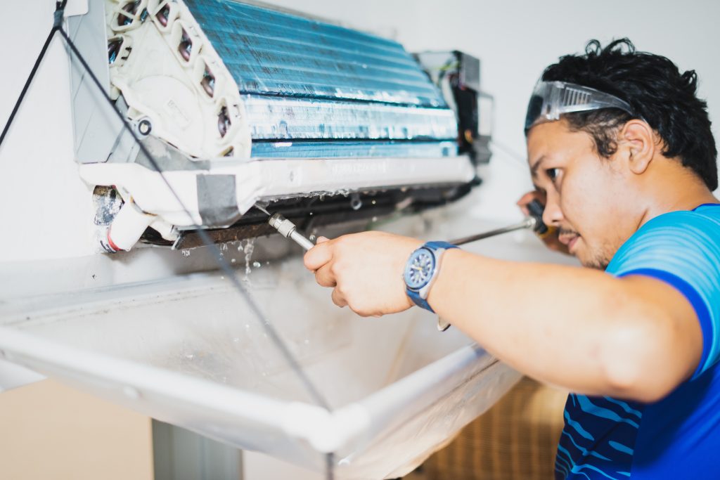 Professional AC Repair PG service technician cleaning an air conditioner unit, ensuring efficient cooling for optimal performance in your home.