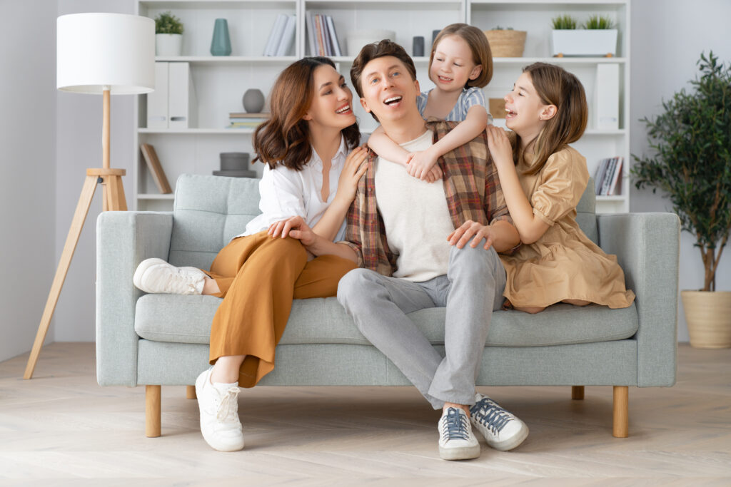 Happy family of four enjoying time together at home. Consider AC maintenance for your home to ensure comfort and prevent issues.